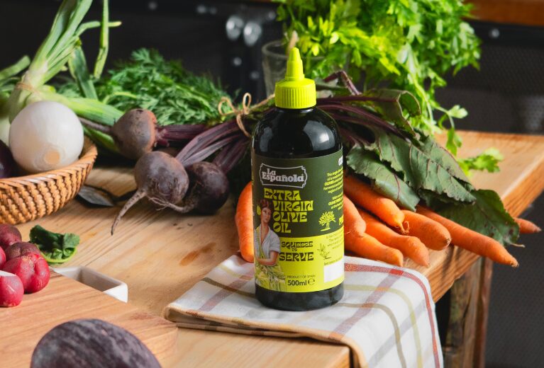 Squeezy Extra Virgin olive oil squeeze bottle on a wooden table of fresh vegetables